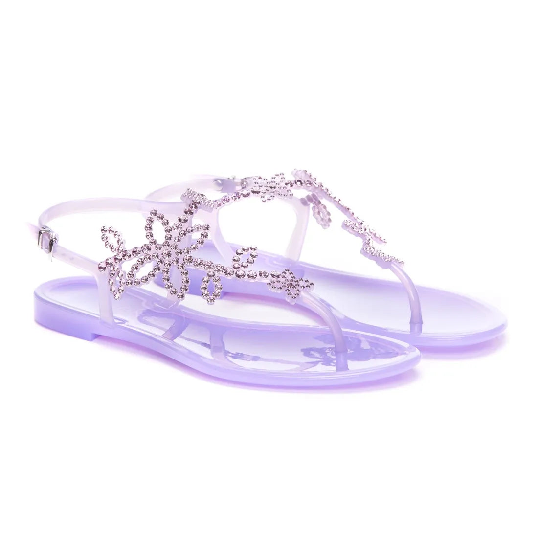 A pair of purple flat sandals with rhinestone embellishments on the straps.